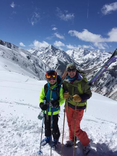 Krista Crabtree and her daughter pose for a picture after hiking with skis on their backs, with incredible Aspen-area mountain in the background.